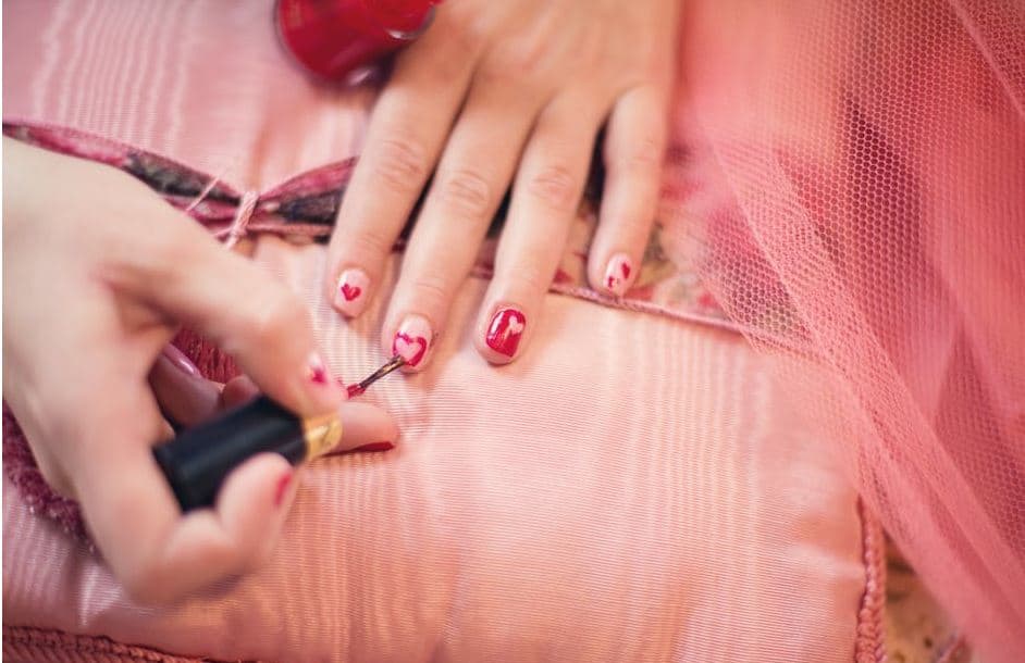 A woman painting her nails at home to save money.