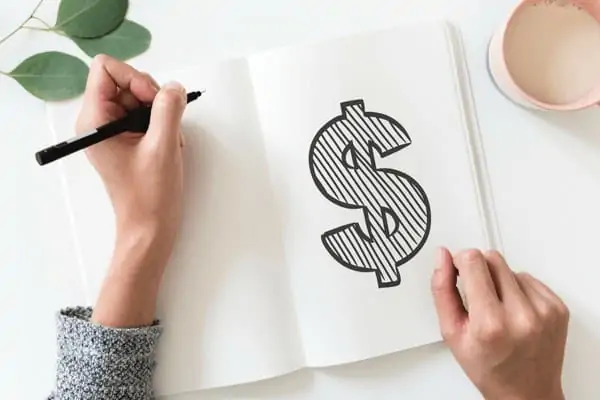 A women drawing a big dollar sign on paper