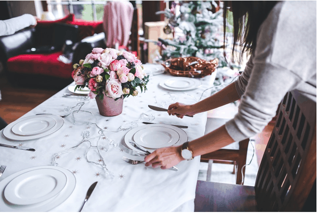 A women setting the table for a fancy holiday meal.
