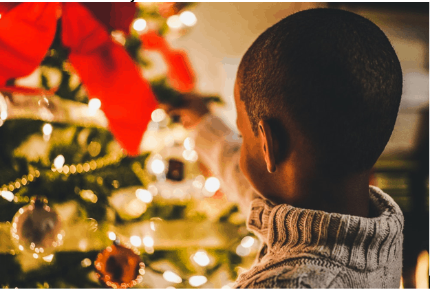 Young boy hanging Christmas decorations on a Christmas tree.