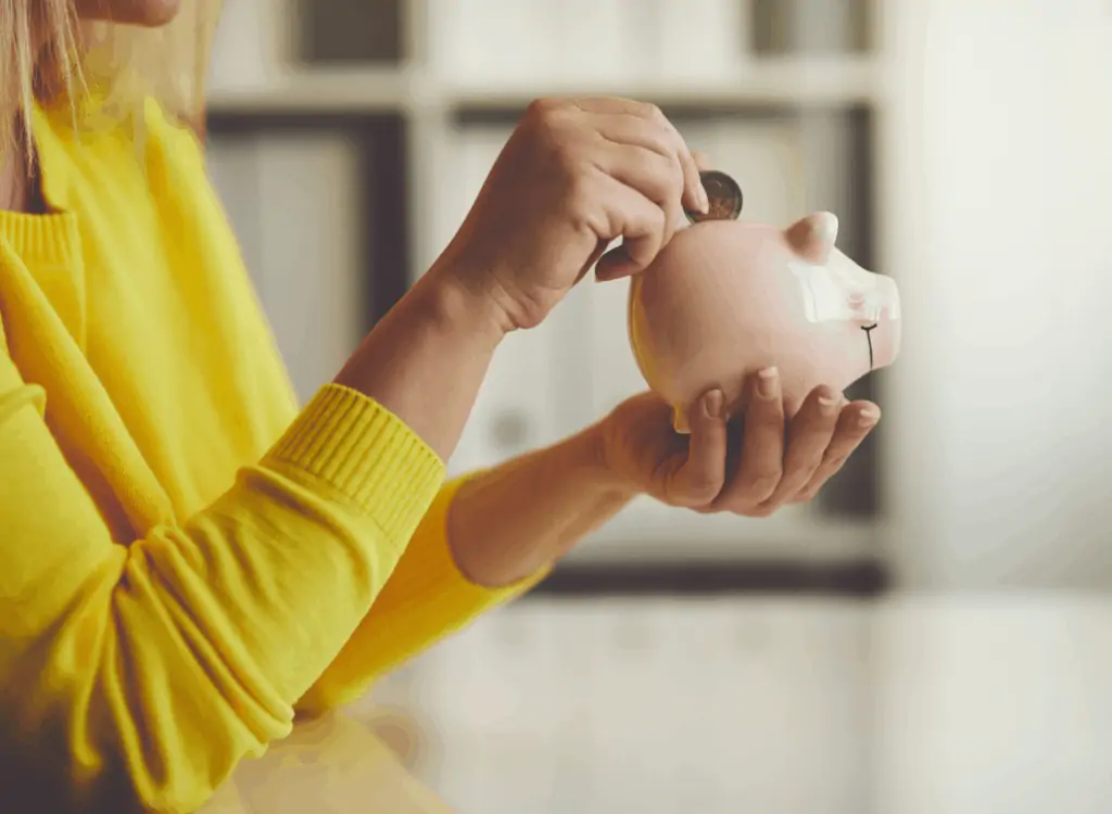 A woman putting coins into a piggy bank