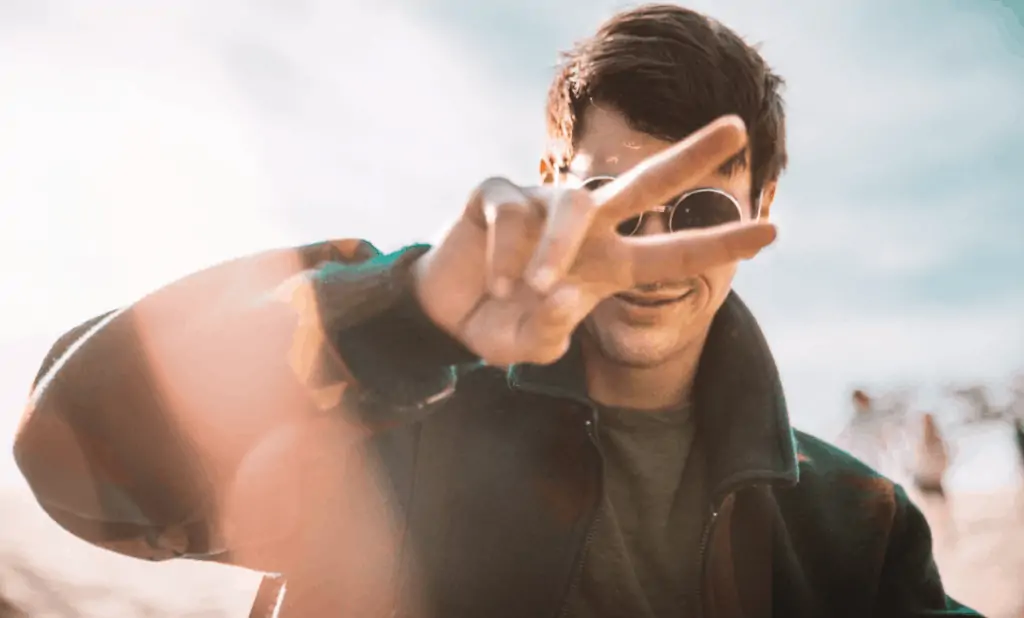 A man wearing sunglasses giving the peace sign.