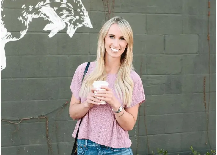 A woman smiling holding a coffee