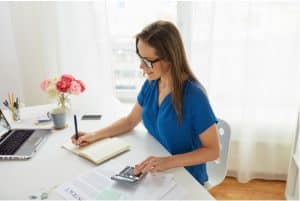 A woman wearing a blue shirt working from home at her desk
