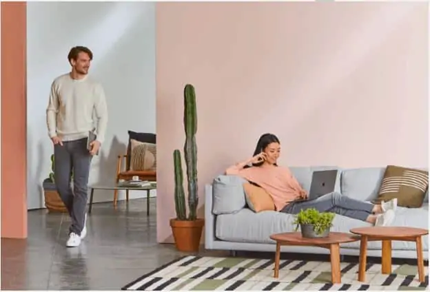 standing man and a woman on the couch using her laptop to look for part time online jobs