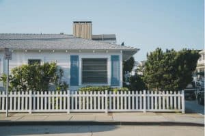A white house with blue shutters and white fence in foreclosure