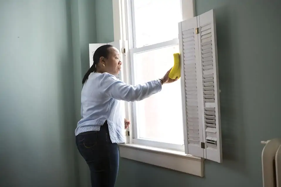 A woman cleaning windows in a house to earn money