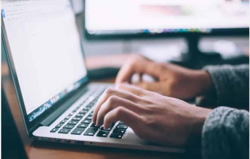 person sitting at their desk on their laptop working on transcription 