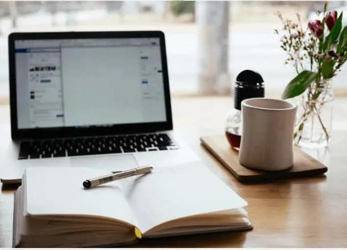 picture of a book and laptop on a desk about working on a blog 