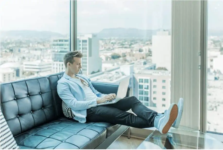 man sitting on a couch working on a laptop 