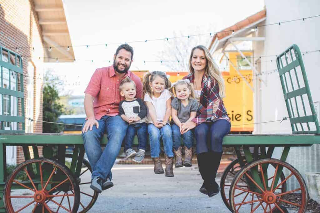 A family of five sitting on a wagon and flip items at a flea market