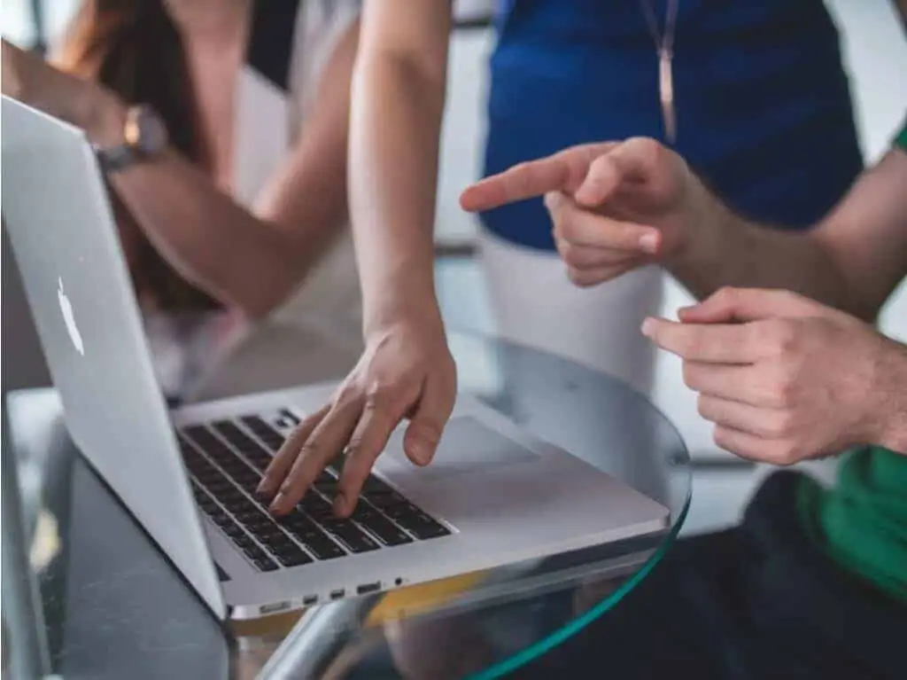 3 people working on a laptop together