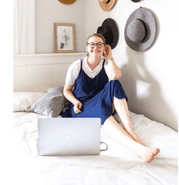 A woman sitting on her bed working from home.