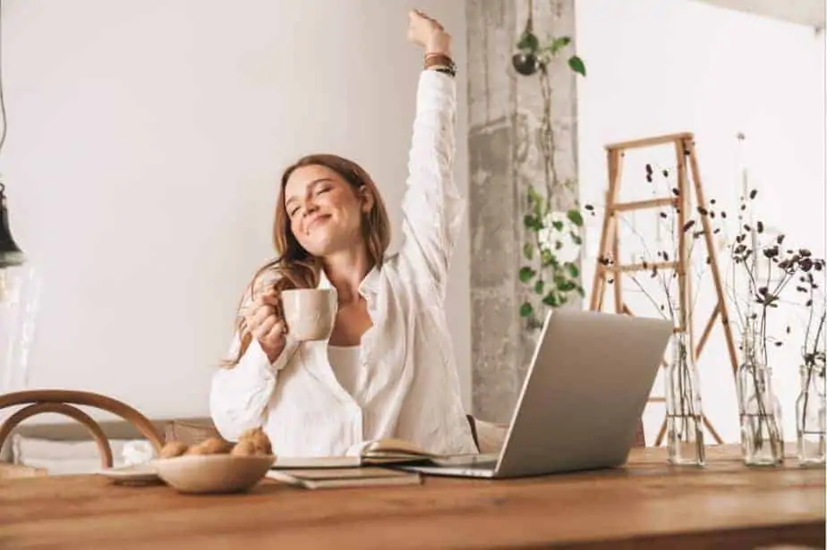 A woman happily drinking coffee while working from home.