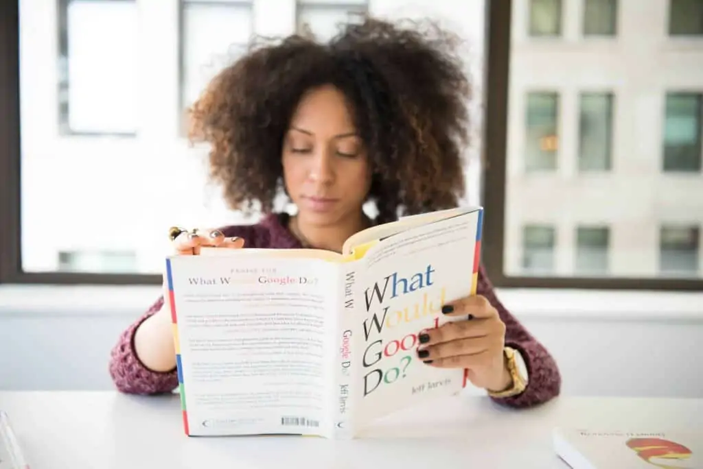 A woman reading the book "What Would Google Do? at a desk