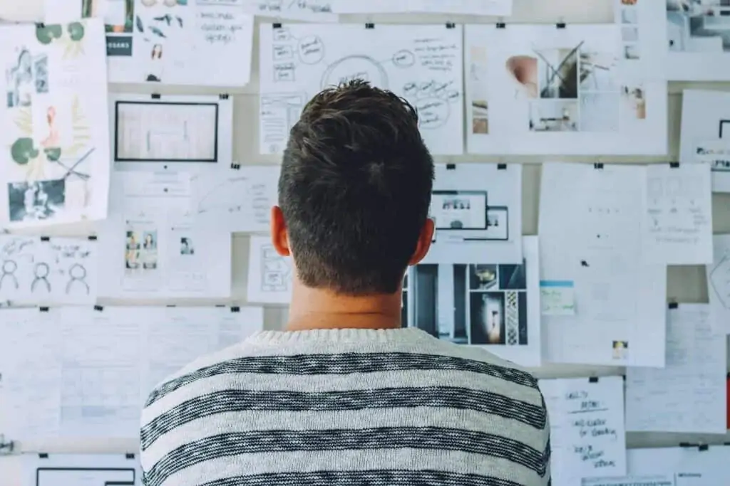 A man looking at a billboard filled with papers