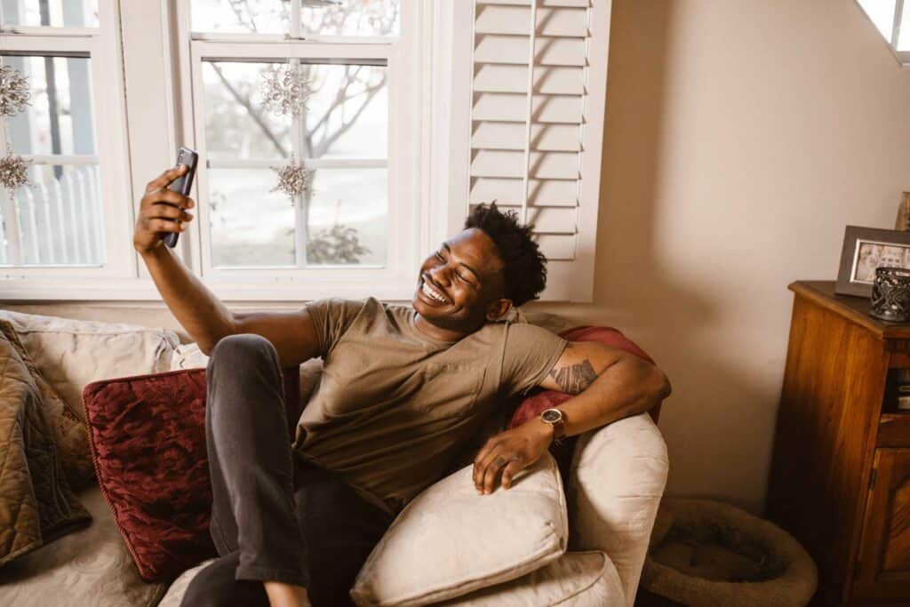 man at home looking at his phone smiling