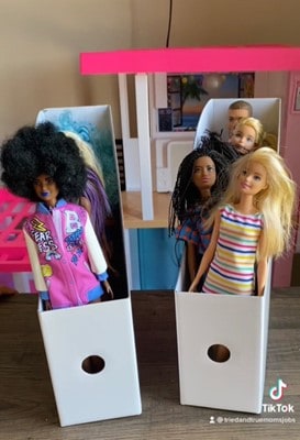 Barbies organized in cardboard holders.