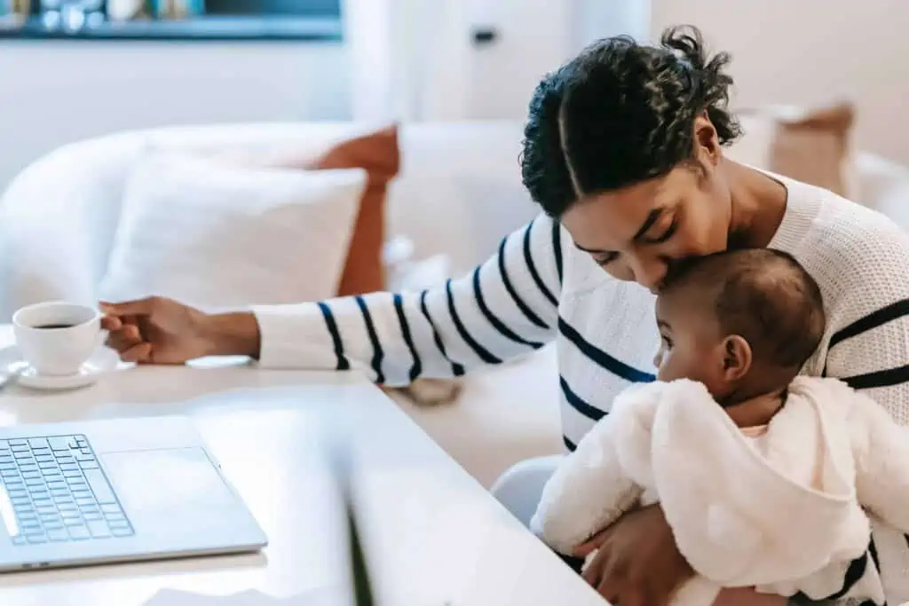 Mom at home with her baby working at a computer as a hobby