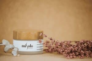 A jar of cream with pink flowers next to it