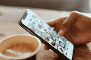 A person on their phone with a cup of coffee