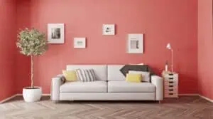 A white couch with pillows in front of a pink wall