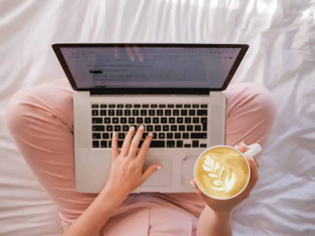 Woman working on a laptop with coffee in her hand